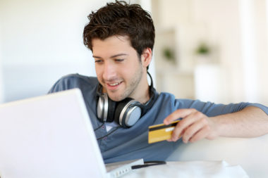 Young man paying his student loans with a credit card.