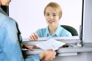 A check cashier receiving a check from a person to cash.